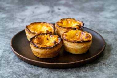 Pasteis de Nata veya Belem Tart. Tahta tabakta yumurta, tarçın, şeker ve un ile yapılmış Portekiz kreması. Geleneksel Tatlı.