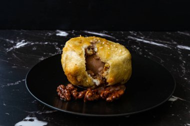 Çikolatalı kızarmış dondurma ve siyah tabakta kavrulmuş ceviz. Geleneksel Organik Tatlı.