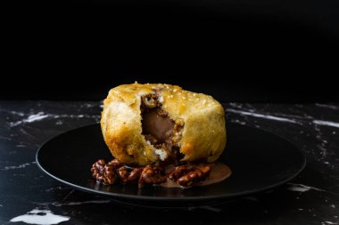 Çikolatalı kızarmış dondurma ve siyah tabakta kavrulmuş ceviz. Geleneksel Organik Tatlı.