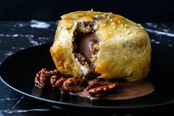 Çikolatalı kızarmış dondurma ve siyah tabakta kavrulmuş ceviz. Geleneksel Organik Tatlı.