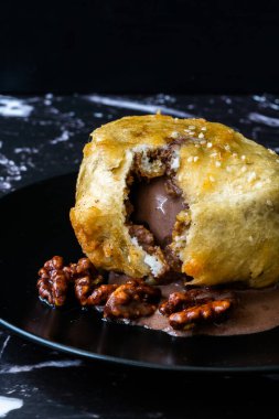 Çikolatalı kızarmış dondurma ve siyah tabakta kavrulmuş ceviz. Geleneksel Organik Tatlı.