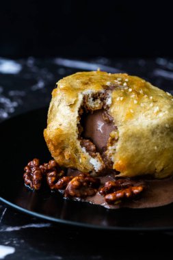 Çikolatalı kızarmış dondurma ve siyah tabakta kavrulmuş ceviz. Geleneksel Organik Tatlı.