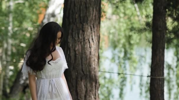 Дівчина хвилює кучеряве волосся в лісі — стокове відео