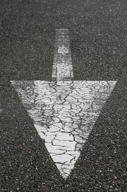 Asfalttaki desenli beyaz ok. Beyaz sokak oku trafiğin yönünü gösteriyor.