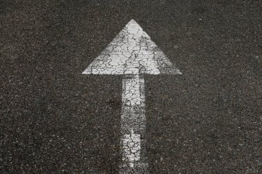 Asfalttaki eski desenli beyaz ok. Beyaz sokak oku trafiğin yönünü gösteriyor.