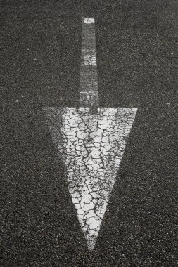 Asfalttaki desenli beyaz ok. Beyaz sokak oku trafiğin yönünü gösteriyor.