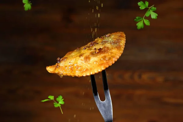 fried pie with meat on the fork with spices