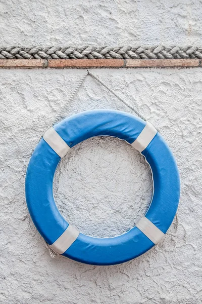 Bouée de sauvetage bleue sur le mur blanc — Photo