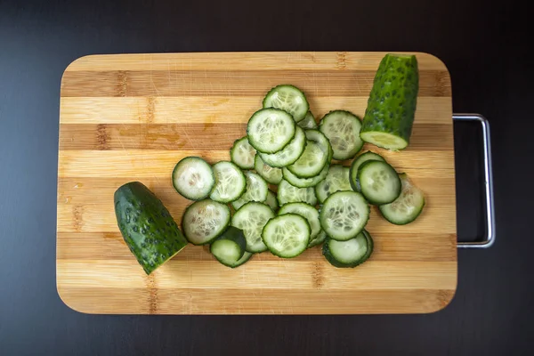 Pepino en rodajas acostado en una tabla de madera . — Foto de Stock