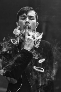 Genç yakışıklı beyaz adam Buhar Yüzükler izin verdi. Vaping. Elektronik sigara. Siyah ve beyaz fotoğraf.