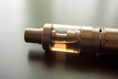 Masanın üzerine sıvı tankı ile elektronik sigara. Vaping. Yakın çekim. Biter.