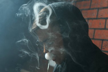 Genç yakışıklı beyaz adam admiting puffs üzerinden elektronik sigara Buhar olduğunu. Vaping. Müzik genç.