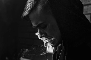 Genç yakışıklı beyaz adam admiting puffs üzerinden elektronik sigara Buhar olduğunu. Vaping. Genç müzik. Siyah ve beyaz fotoğraf.