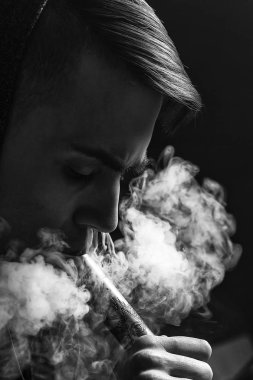 Genç yakışıklı beyaz adam admiting puffs üzerinden elektronik sigara Buhar olduğunu. Vaping. Genç müzik. Siyah ve beyaz fotoğraf.