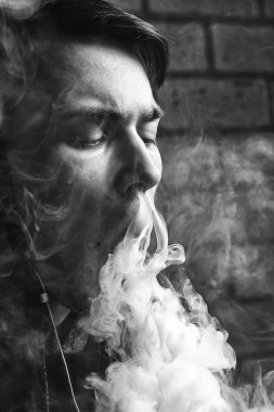 Genç yakışıklı beyaz adam admiting puffs üzerinden elektronik sigara Buhar olduğunu. Vaping. Genç müzik. Siyah ve beyaz fotoğraf.