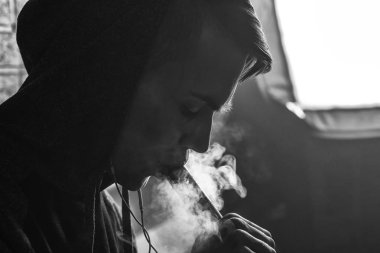 Genç yakışıklı beyaz adam admiting puffs üzerinden elektronik sigara Buhar olduğunu. Vaping. Genç müzik. Siyah ve beyaz fotoğraf.