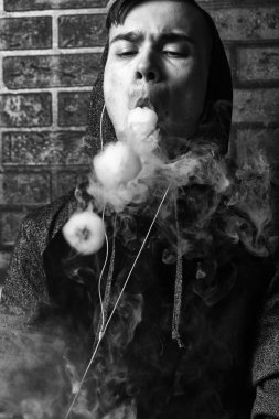 Genç yakışıklı beyaz adam admiting puffs üzerinden elektronik sigara Buhar olduğunu. Vaping. Genç müzik. Siyah ve beyaz fotoğraf.