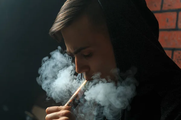 Jeune homme blanc beau admire les bouffées de vapeur de la cigarette électronique. Vaping. Adolescent écoutant de la musique . — Photo