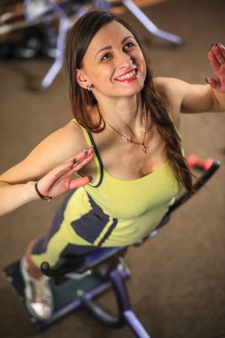 Genç güzel kız bir sarı beyaz ve gri spor takım elbise eğitim aparatı fitness Club egzersizleri yapıyor.