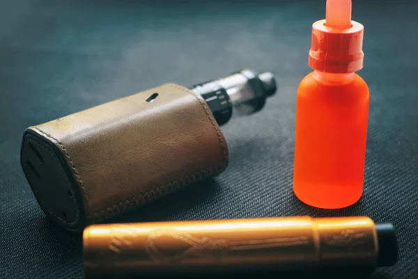 Vape. Flaska med e-vätska och nikotine och elektronisk cigarett mod på svart textil. Personlig spridare. — Stockfoto