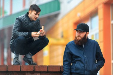 Vape. İki genç insanlar stand ve elektronik sigara sokakta bulutlu bir günde.