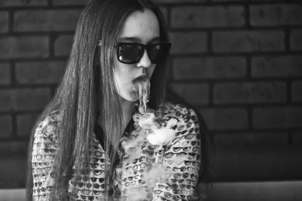 Vape. Stilig vit flicka i solglasögon är admiting puffar av ånga från elektronisk cigarett. — Stockfoto