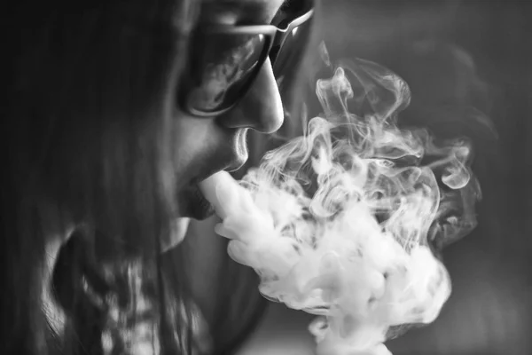 Vape. Jeune belle fille blanche dans les lunettes de soleil admire les bouffées de vapeur de la cigarette électronique . — Photo