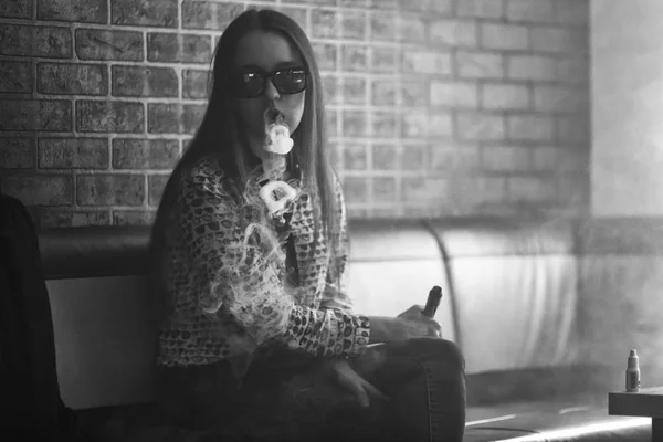 Vape. Menina branca bonito jovem em óculos de sol está admitindo sopros de vapor do cigarro eletrônico . — Fotografia de Stock