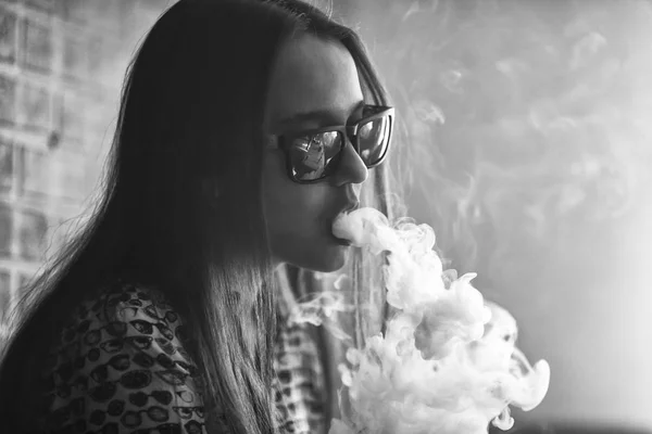 VAPE. Mladý pohledný bílá dívka v sluneční brýle se hlásíme obláčky páry z elektronické cigarety. — Stock fotografie