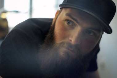 Bir kap içinde bir genç sakallı adam dövme salon bir kanepede yatıyor.