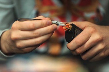 Vape satış sonrası hizmet e-sigara. Erkek el elektronik sigara bobinleri pincette ile düzenler. Parlak sarmal.
