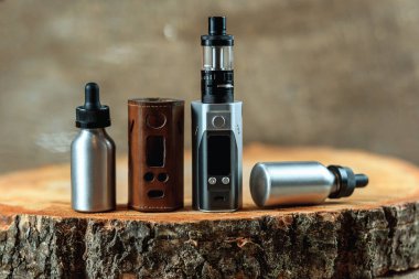 Vape. Bir elektronik sigara mod, deri çanta ve e-sıvı ahşap bir masa ile iki alüminyum şişe. Kişisel Buharlaştırıcı.