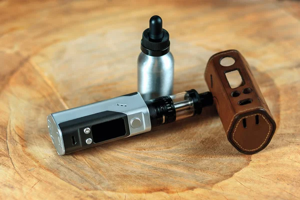 Vape. Bir elektronik sigara mod, deri çantası ve alüminyum şişe ile e-sıvı ahşap bir masa üzerinde. Kişisel Buharlaştırıcı.