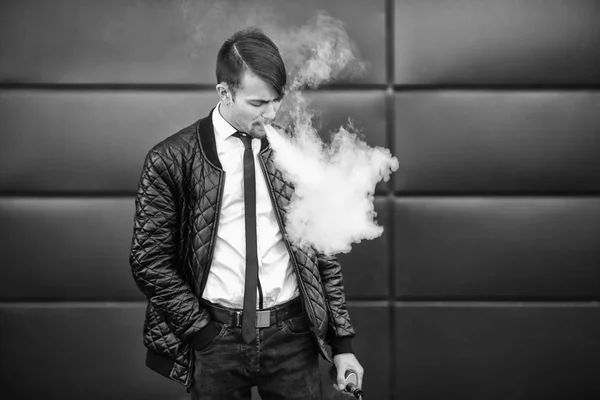 Vape człowieka. Portret przystojny młody biały facet z nowoczesną fryzurę vaping i najmu off steam od elektroniczny papieros. Czarno-białe zdjęcie. — Zdjęcie stockowe
