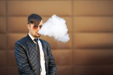 Vape adam. Havacı güneş gözlüğü vaping fütüristik kentsel arka plan karşısında elektronik sigara içinde modern saç kesimi ile yakışıklı genç bir beyaz adam portresi.