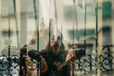 Vape adam. Çift pozlama. Hood vaping ve vintage bir metal geçit yakınındaki elektronik sigara buhar kapalı icar yakışıklı genç bir beyaz adam fotoğrafı.