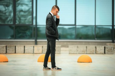 Havacı güneş gözlüğü ve gündüz sokakta sigara kulaklık modern saç kesimi ile yakışıklı bir genç beyaz adamın Portret.