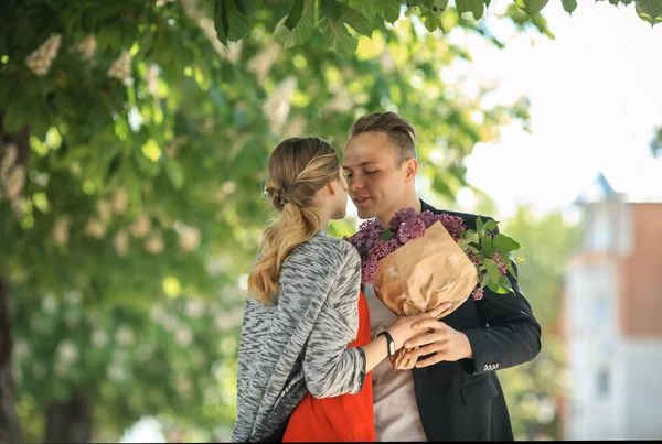 Casal apaixonado no banco com flores roxas . — Fotografia de Stock