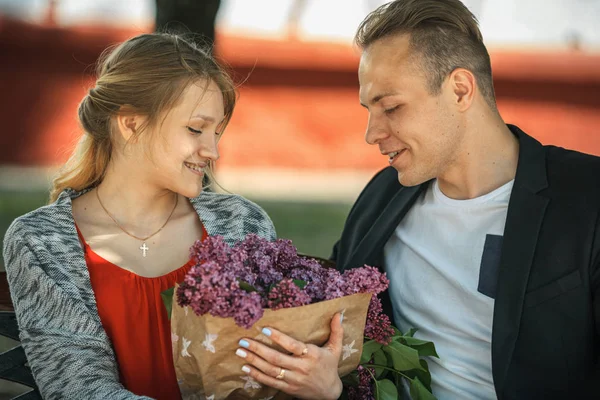 Pár v lásce na lavici, fialové květy. — Stock fotografie