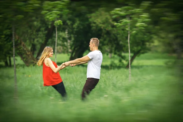 Het verliefde paar is ingeschakeld op een grasveld in het stadspark. Hou in beweging. Wazig. — Stockfoto