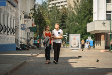 Sevgi dolu bir çift bir şehir bir güneşli yaz gününde sokak boyunca elini kolunu sallaya dönüyor. Genç erkek ve kız.