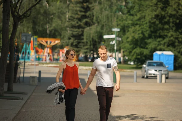 Ένα ζευγάρι ερωτευμένων βόλτες κατά μήκος το δρόμο σε μια ηλιόλουστη καλοκαιρινή μέρα της πόλης. Νεαρό αγόρι και κορίτσι. — Φωτογραφία Αρχείου