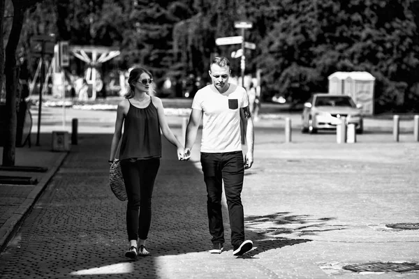 Um casal amoroso passeia ao longo de uma rua da cidade em um dia ensolarado de verão. Rapaz e rapariga. Foto em preto e branco . — Fotografia de Stock