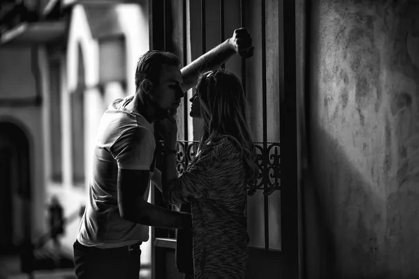 Casal jovem se apaixonando perto de um portão de metal vintage no su — Fotografia de Stock