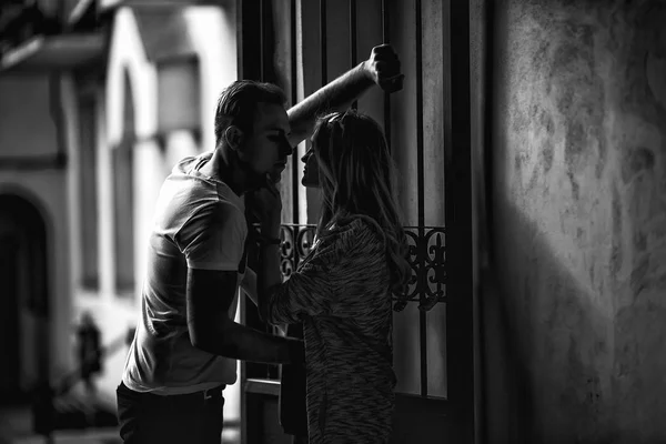 Young couple falling in love near a vintage metal gate in the su