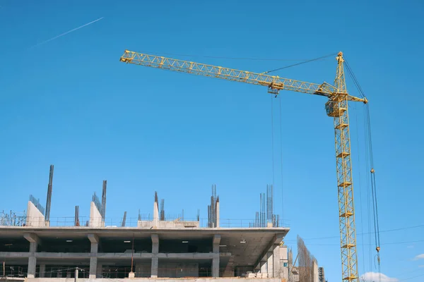 A yellow crane and building under construction against blue sky. — Stock Photo, Image