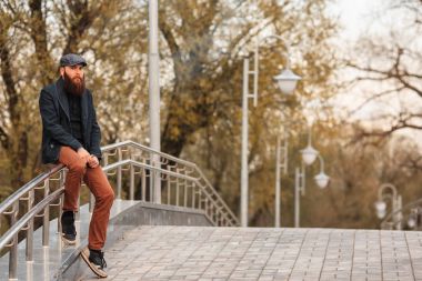 Vape adam gerçek hayatta sakallı. Bir kap vaping elektronik sigara bahar akşam nehirde yakınındaki dolgu üzerinde büyük sakallı genç adam portresi.