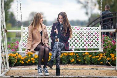 Biseksüel ilişki genç beyaz kızlar sonbaharda sokaktaki bankta. Lezbiyen çift aşk hikayesi. Lgbt topluluğu.