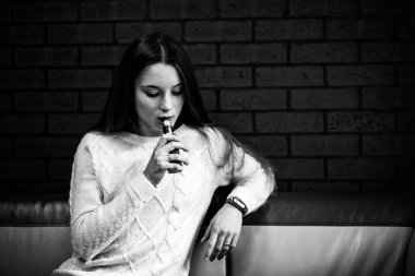 Buharlı genç. İçeride elektronik sigara içen, beyaz tenli, beyaz, genç bir kız. Hayati tehlikesi olan kötü alışkanlık. Vestiyer aktivitesi. Siyah ve beyaz. Kapat..