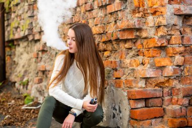 Buharlı genç. Genç, beyaz, beyaz, sorunlu bir genç kız. Elektronik sigara içiyor. Sonbaharda sokakta yıkılmış tuğla bir duvar. Kötü alışkanlık. Vestiyer etkinliği.